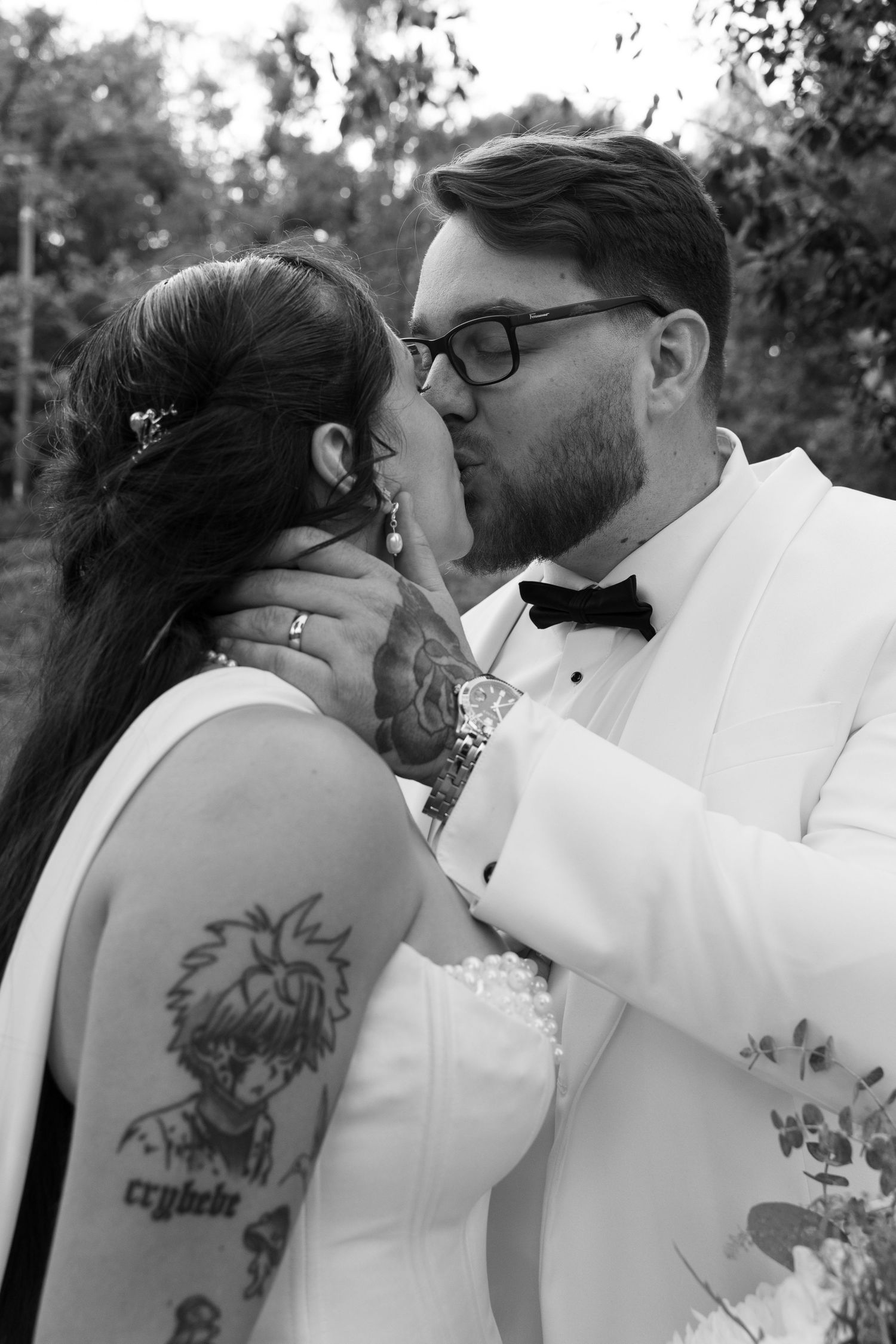 A romantic black and white photo sequence showing a couple embracing and kissing outdoors with visible tattoo art.
