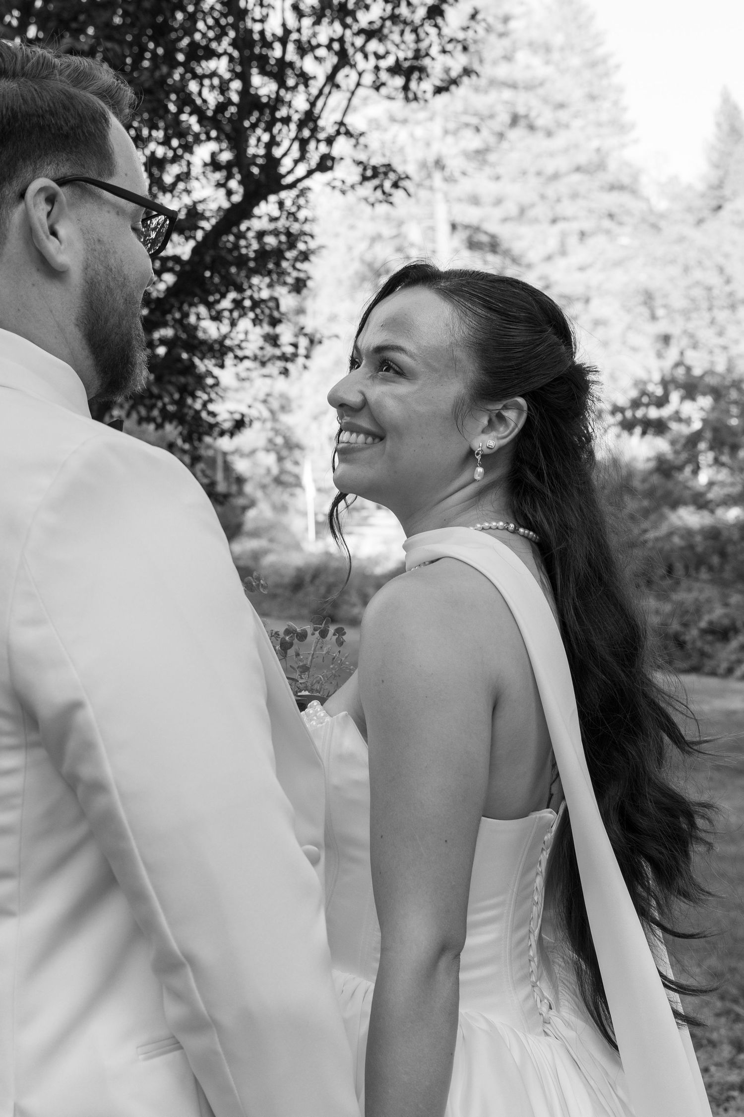 A black and white candid moment captured during a wedding celebration outdoors.