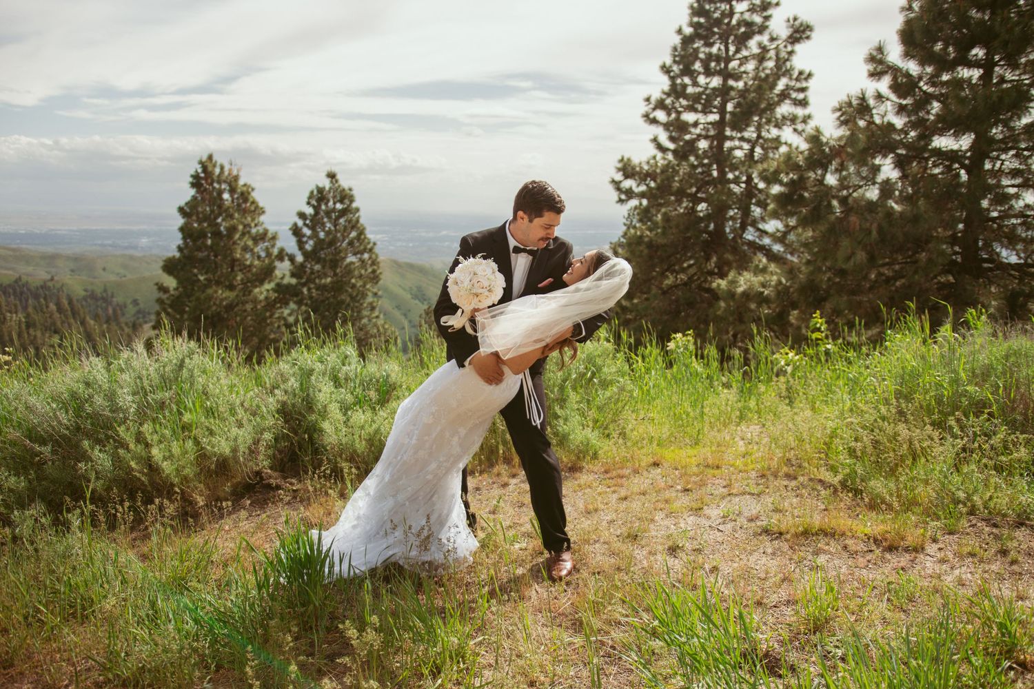 A romantic wedding moment captured on a scenic mountain overlook surrounded by nature.