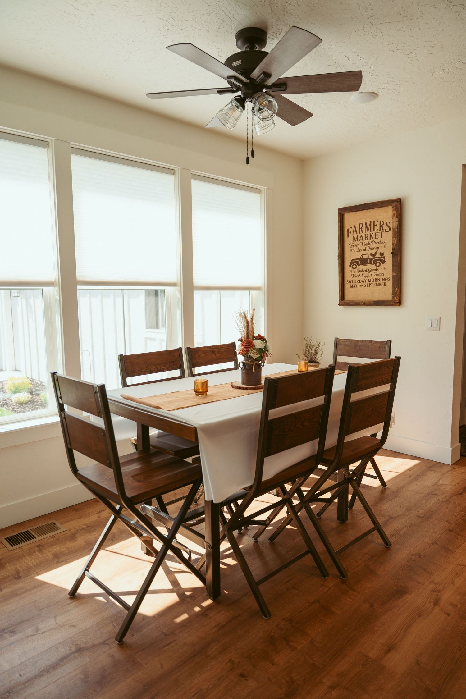 Modern dining area with folding chairs and ceiling fan near large windows.