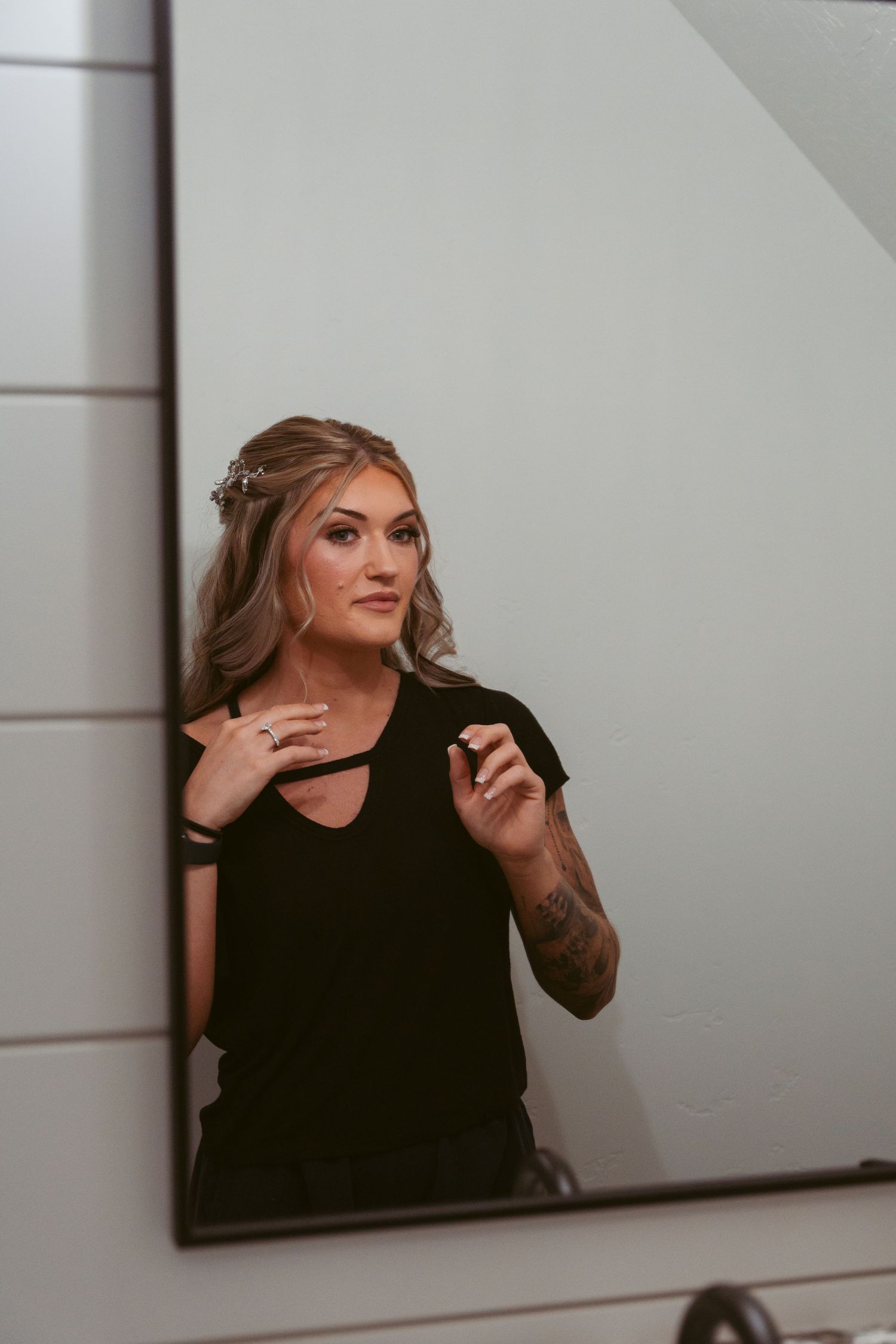 Woman in black top posing against white wall during photo session.