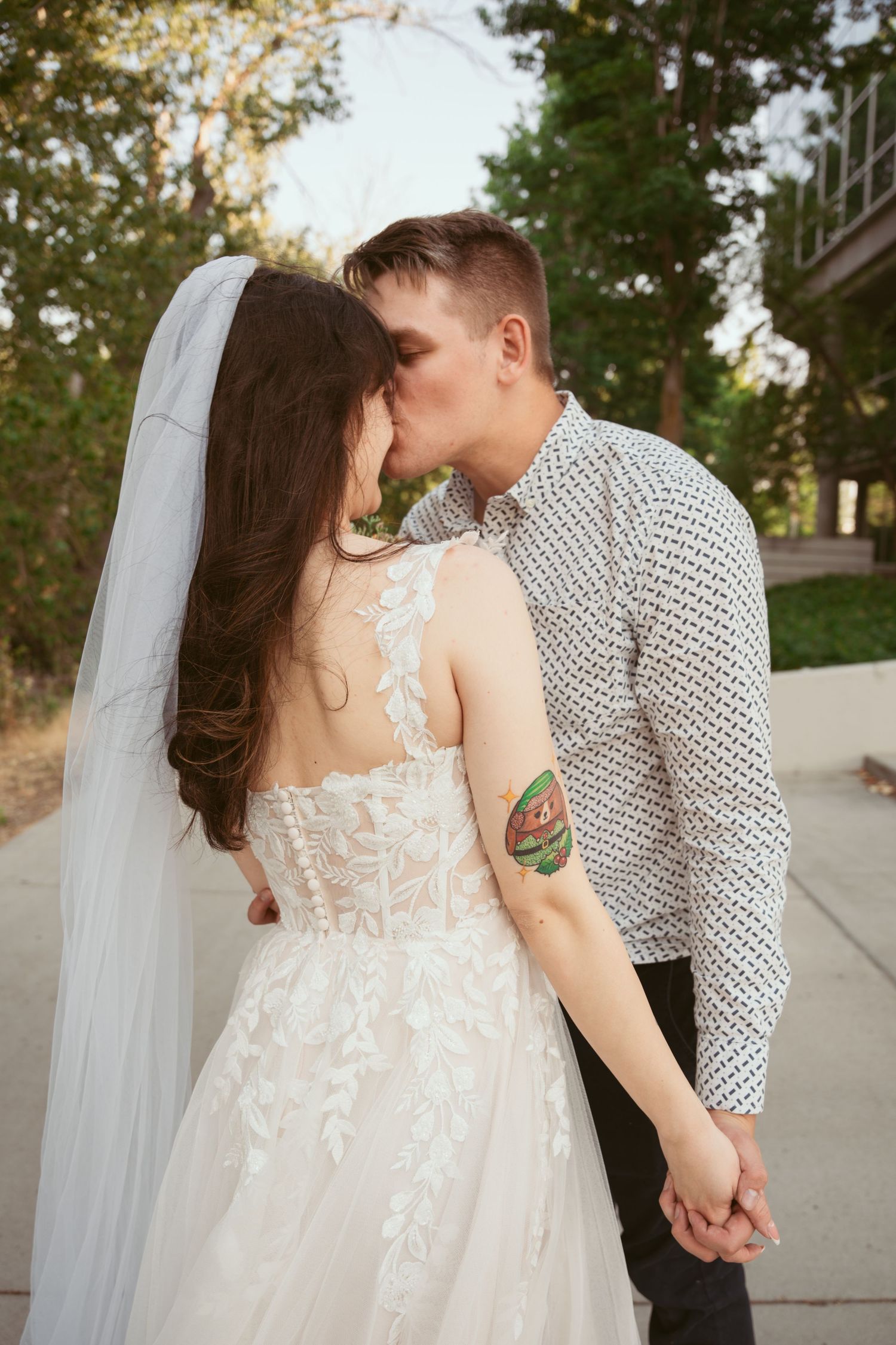 Romantic wedding couple embracing on a concrete path with flowing white dress and polka dot shirt.