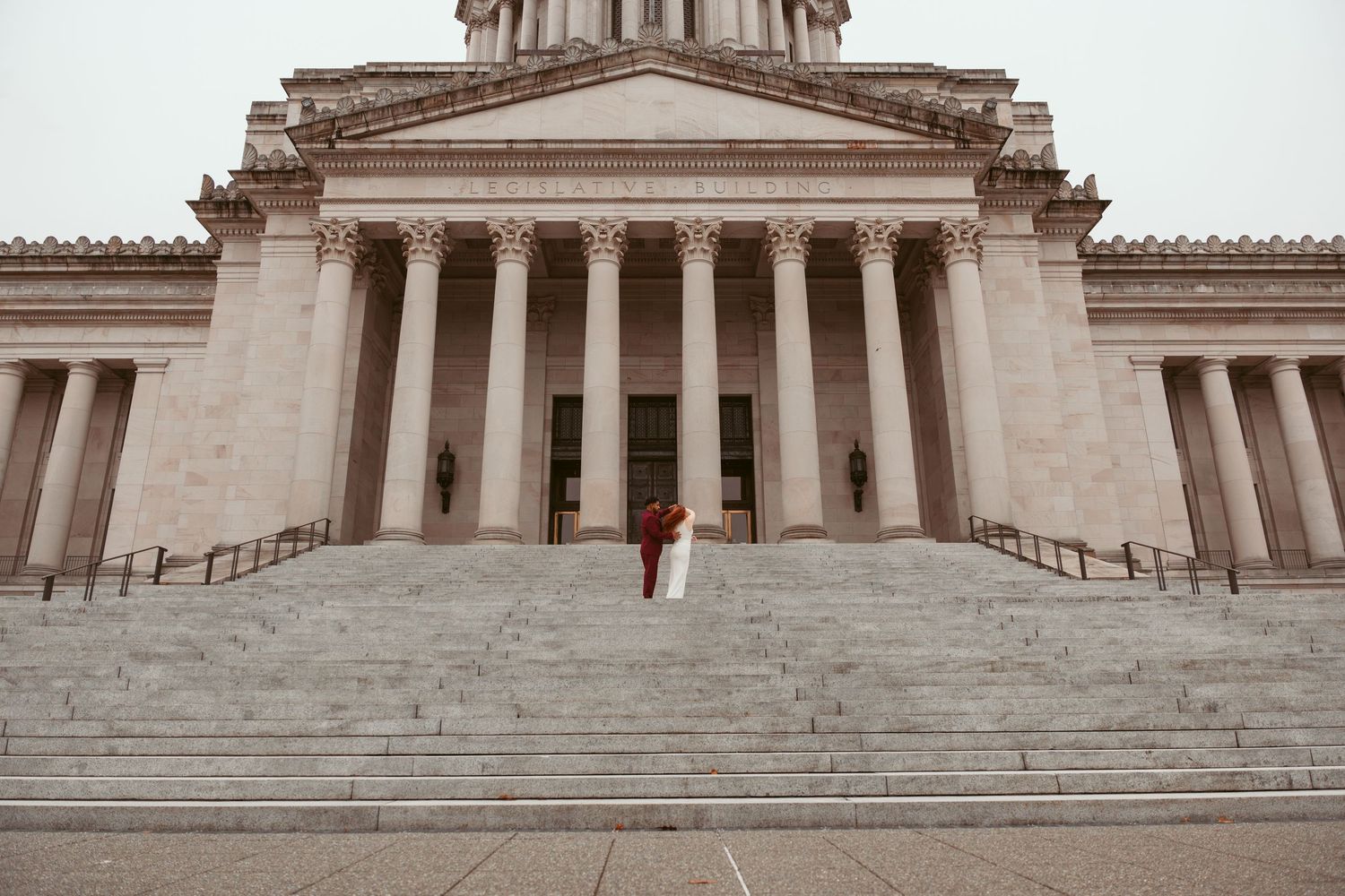 Architectural detail showing grand stone steps leading to a neoclassical building with ornate columns and domed roof.