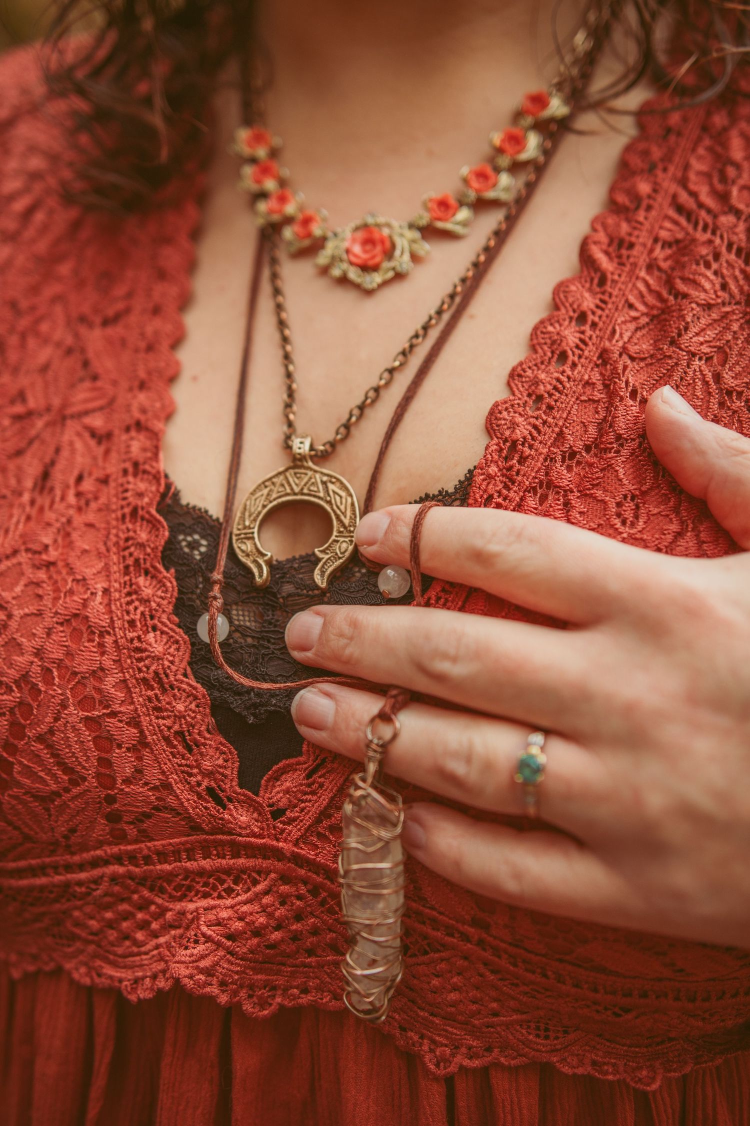Close-up of hands wearing rings against red lace fabric with vintage jewelry details.
