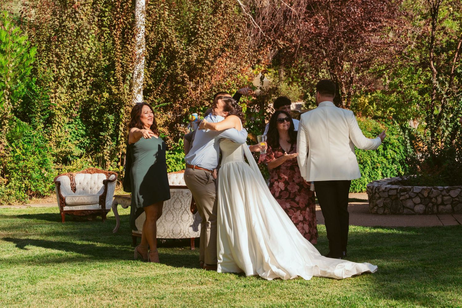 Wedding party members walking through a lush garden setting during a summer celebration.