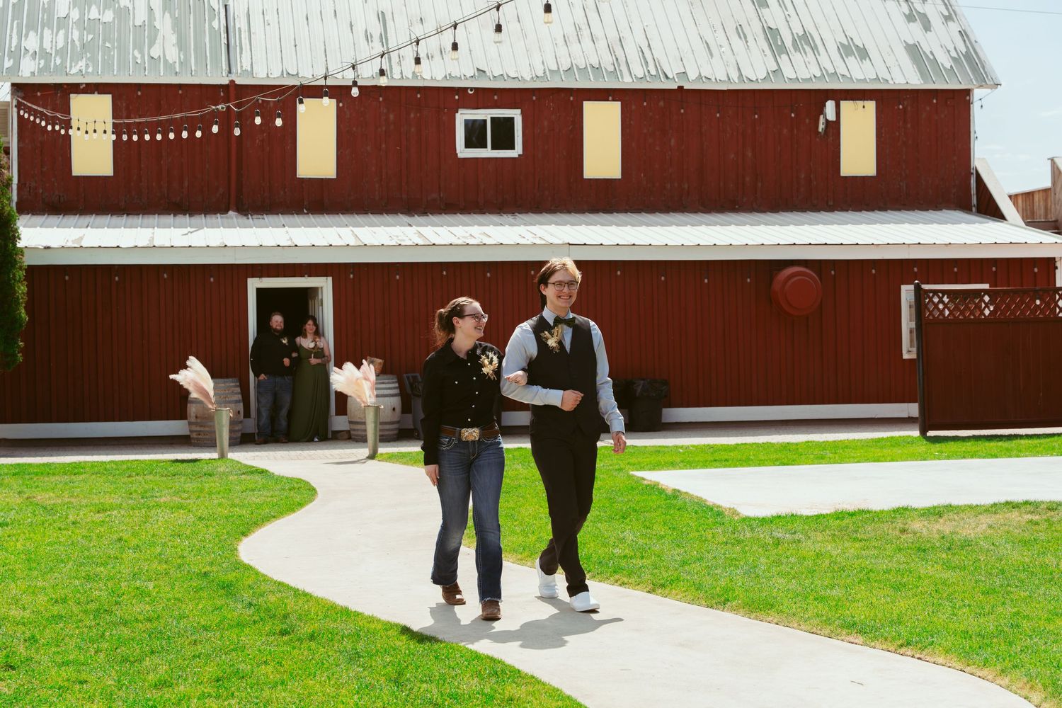 Multiple sequential images of people walking along a pathway beside a large red barn structure.