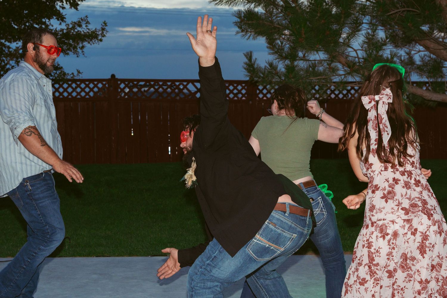 Guests performing synchronized dance moves at an outdoor wedding reception.