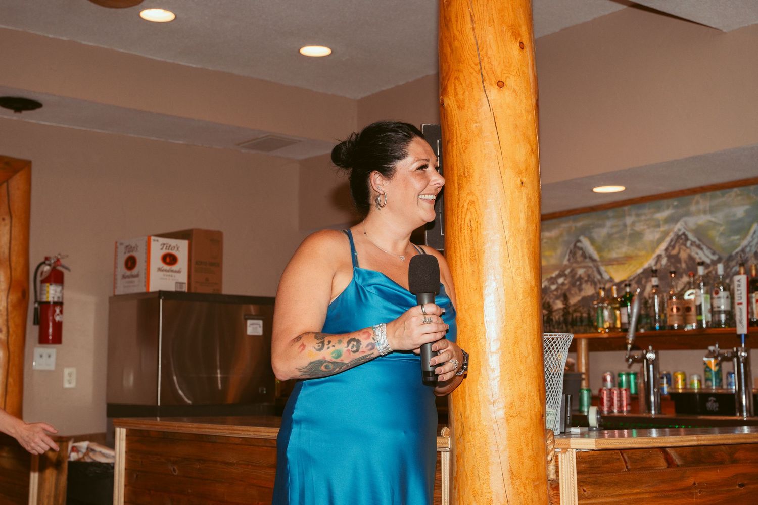 Couple sharing a wedding cake cutting moment in a rustic venue with wooden log pillars.