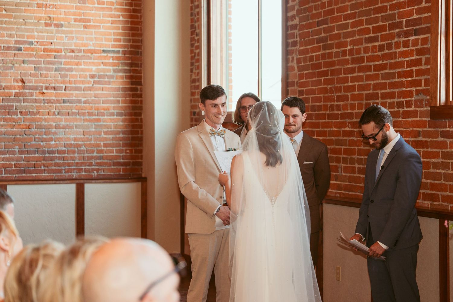 Intimate wedding ceremony moment captured in sunlit brick venue.