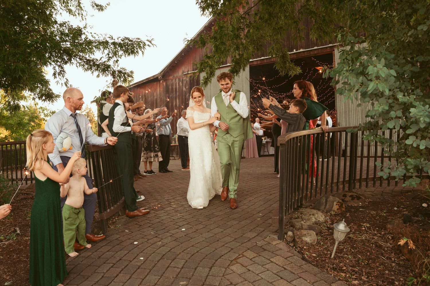 Wedding party celebrating outdoors on a brick pathway during sunset.
