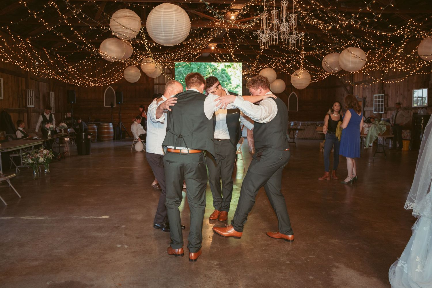 Wedding guests dancing and celebrating under warm twinkle lights and paper lanterns.
