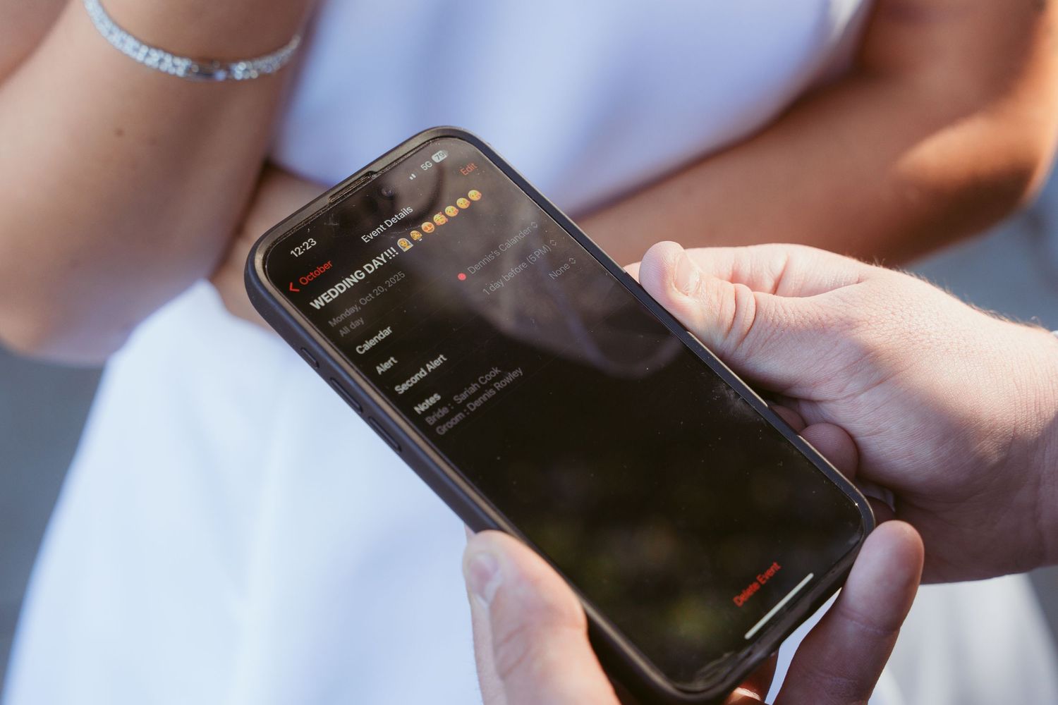 Close-up of hands holding smartphone during wedding ceremony.