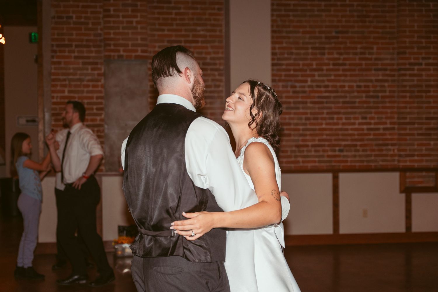 Dancers twirling on the dance floor of a rustic brick venue during a celebration.
