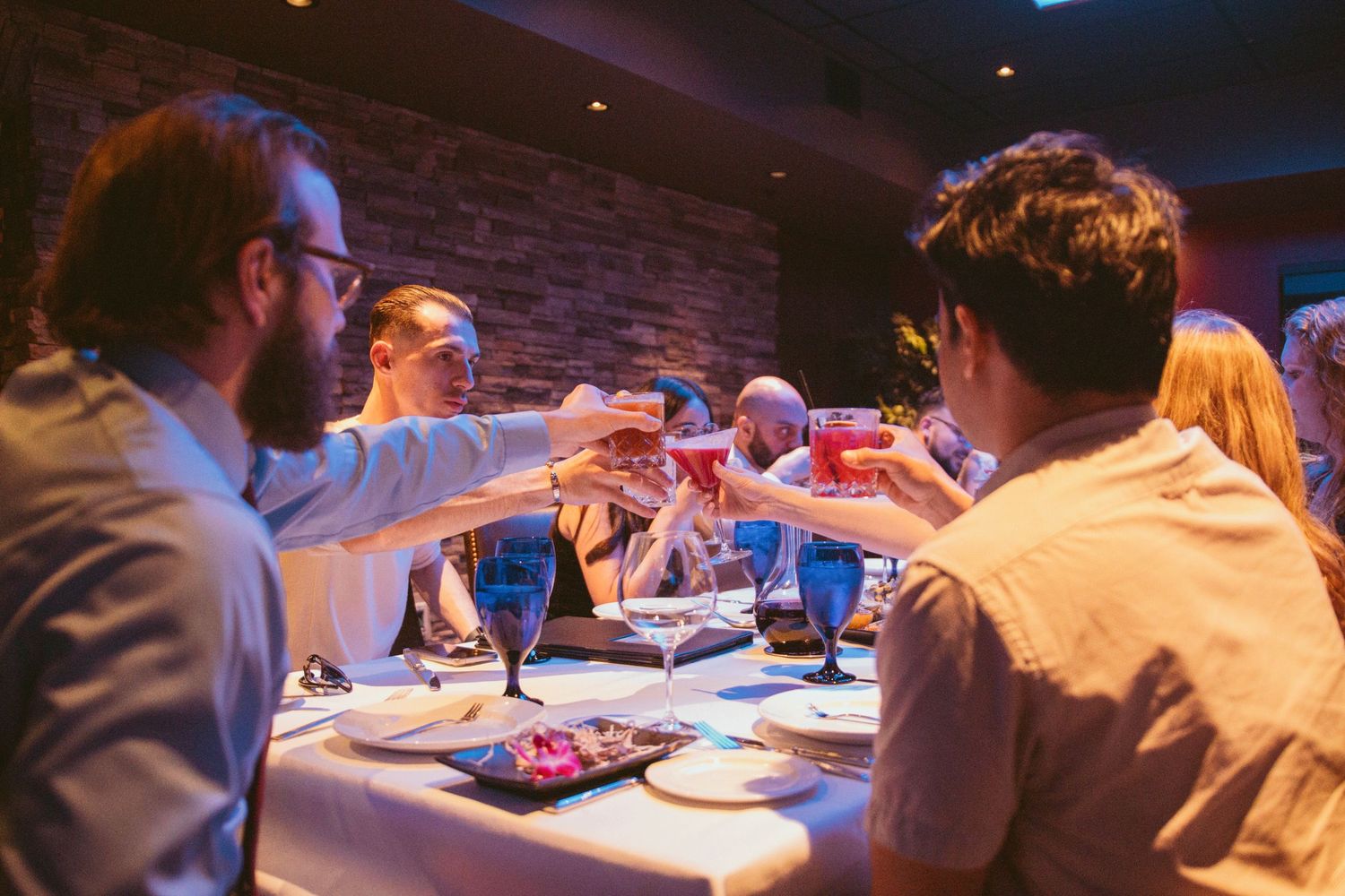 Guests dining at elegant wedding reception with stone walls and ambient lighting.