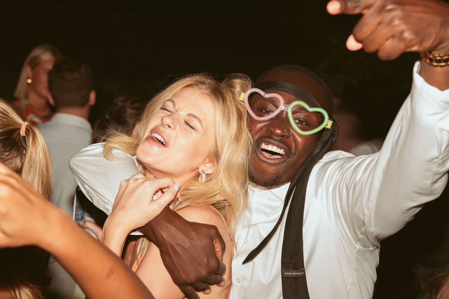 Enthusiastic party guests dancing and laughing during a wedding celebration.