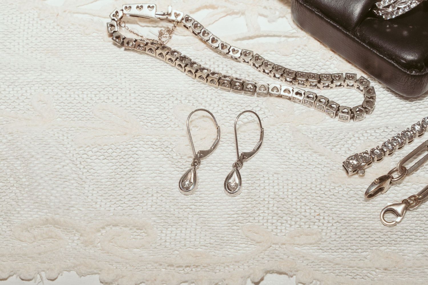 A collection of delicate silver jewelry pieces including necklaces and earrings arranged on a white textured surface.