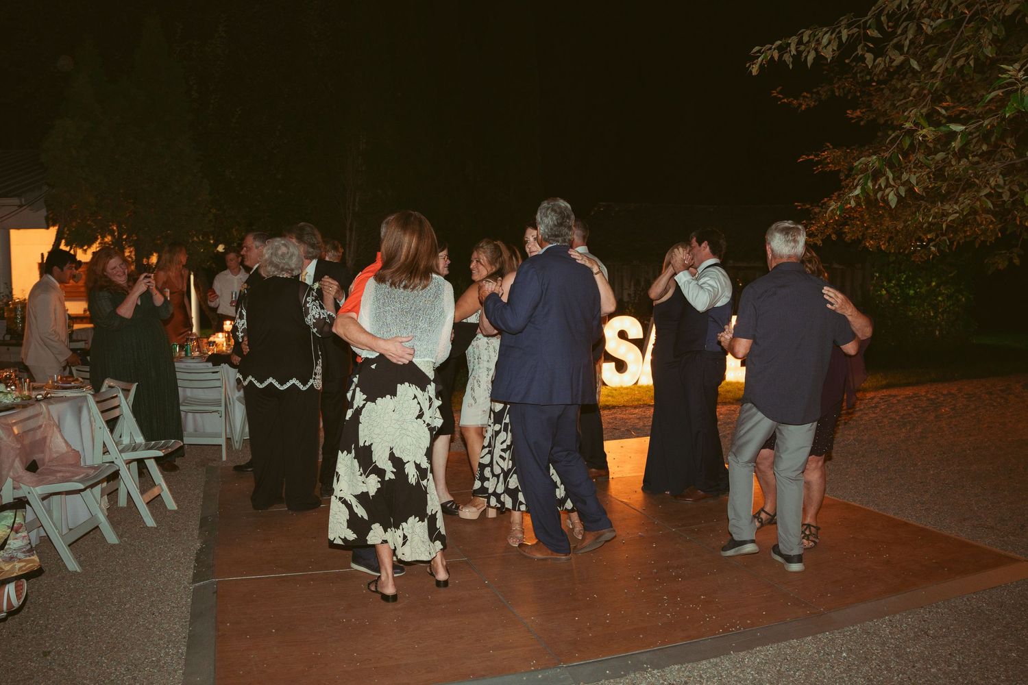 Wedding guests dancing and celebrating on an outdoor dance floor at night.