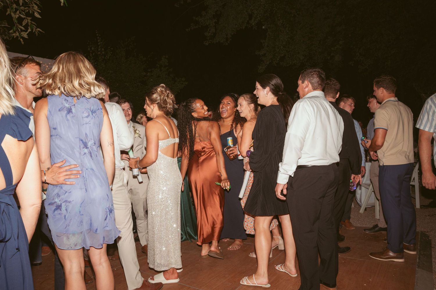 Wedding guests mingling and dancing at an outdoor evening reception.