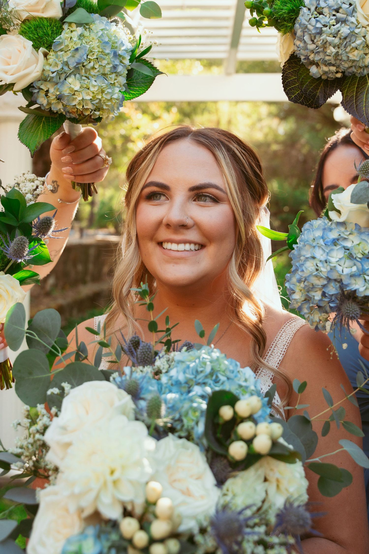 Beautiful wedding bouquet featuring blue hydrangeas and white roses in an outdoor garden setting.