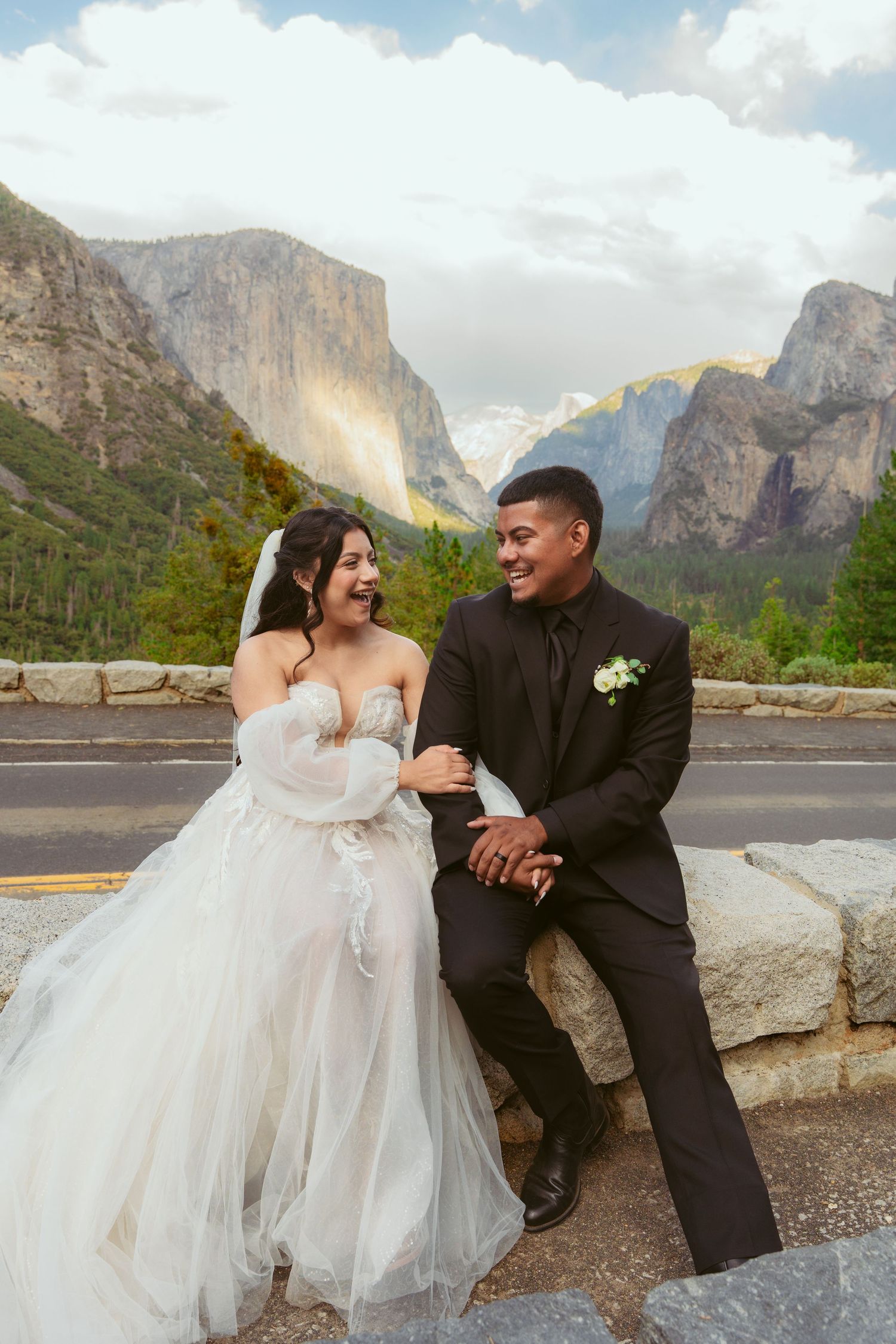 Wedding couple seated on rocks sharing intimate moments with Half Dome visible in the background.