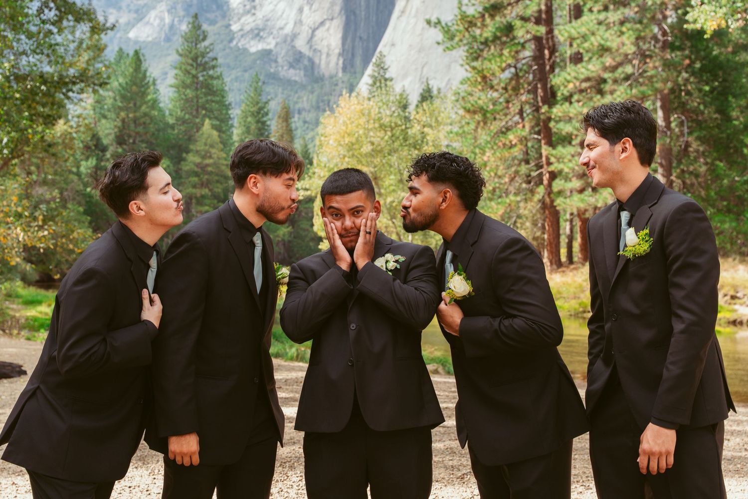 Groomsmen in black suits share laughs and candid moments during outdoor wedding photos.