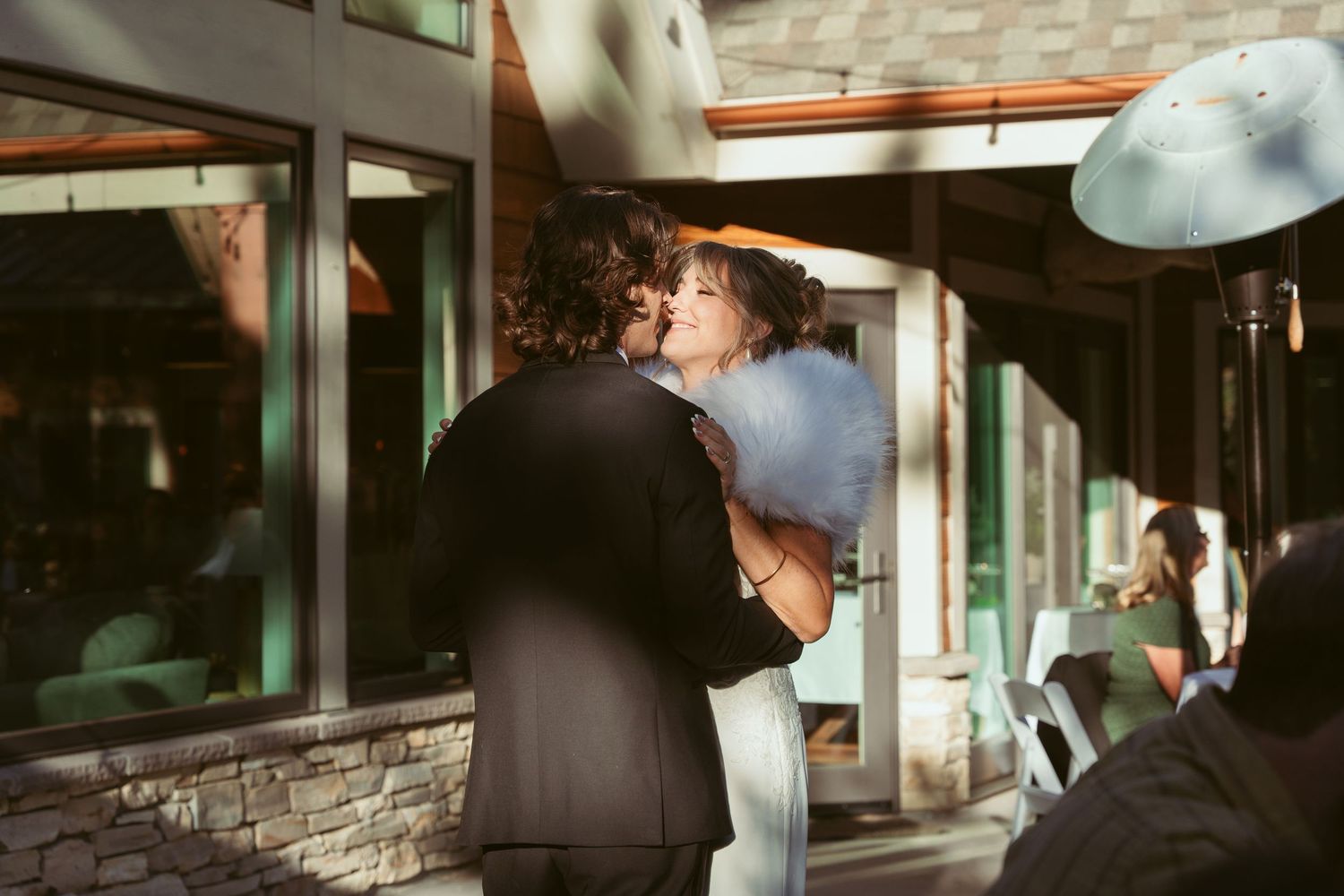A couple shares a dance moment at their wedding with stone walls and glass windows behind them.