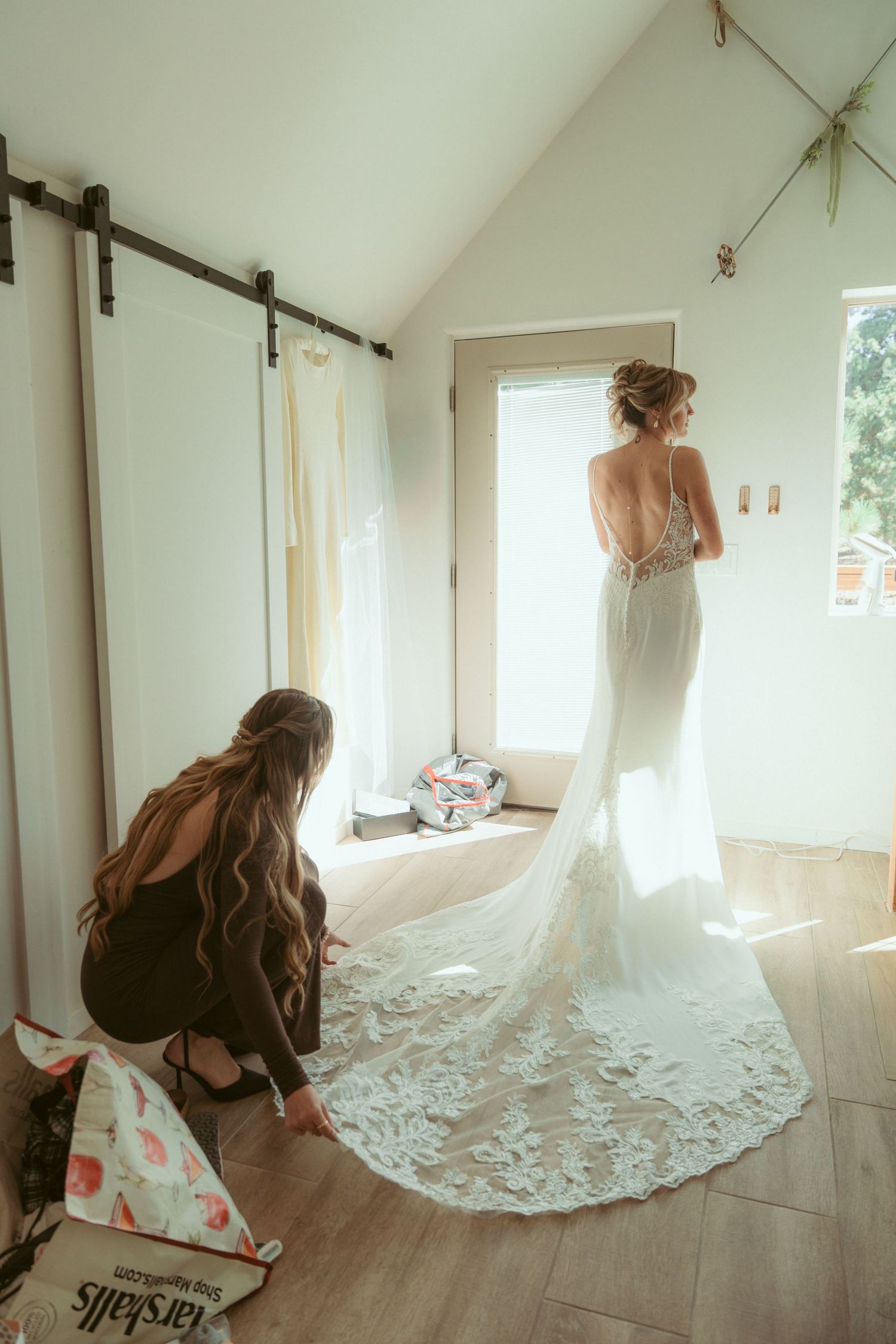 Wedding dress with long lace train photographed in natural window light.