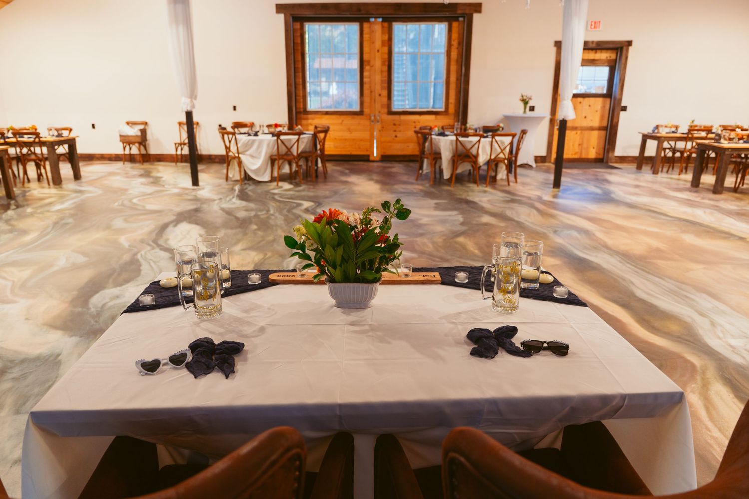 Wedding reception table setup with floral centerpiece and place settings.