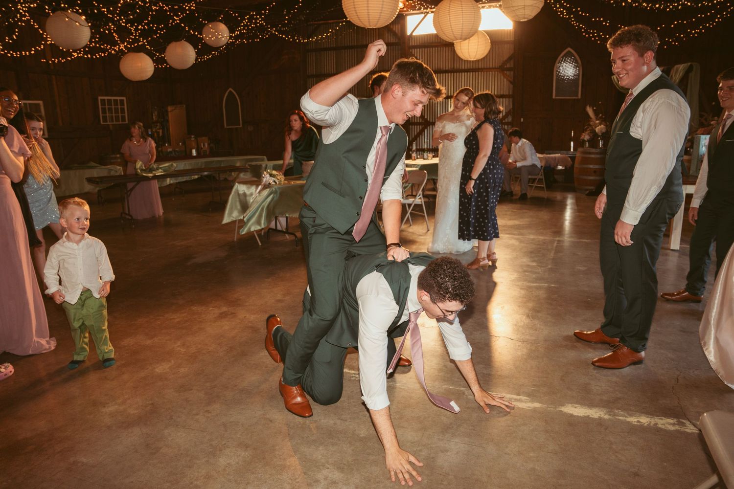 Wedding reception dance party with guests celebrating under warm ambient lighting.