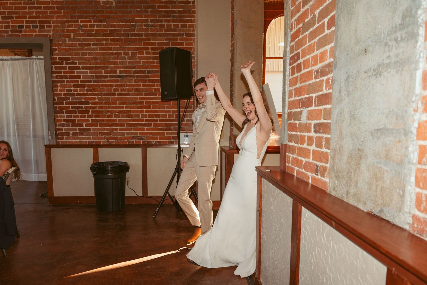 Dancers twirl and spin across a wooden dance floor in a historic brick building.