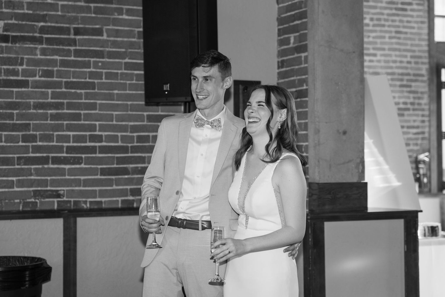 A couple shares a moment together during their wedding reception in a brick-walled venue.