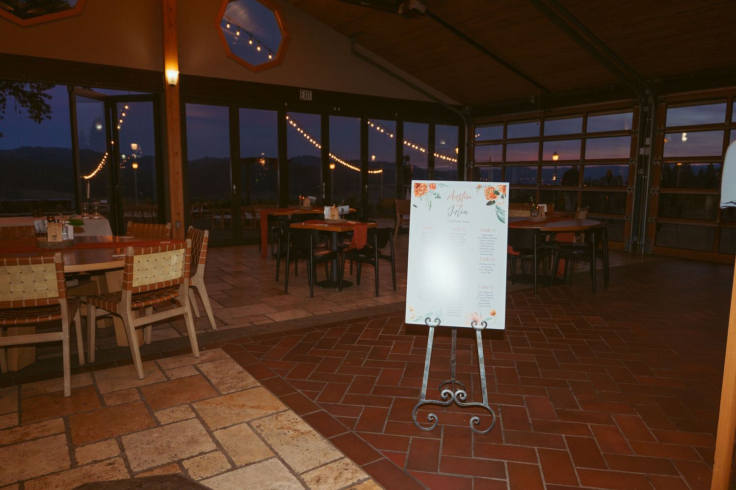Dark reception space with empty tables and a white easel board visible.
