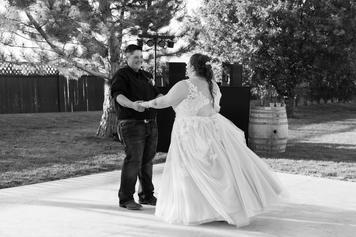 A black and white photo captures a couple dancing at their outdoor wedding reception.