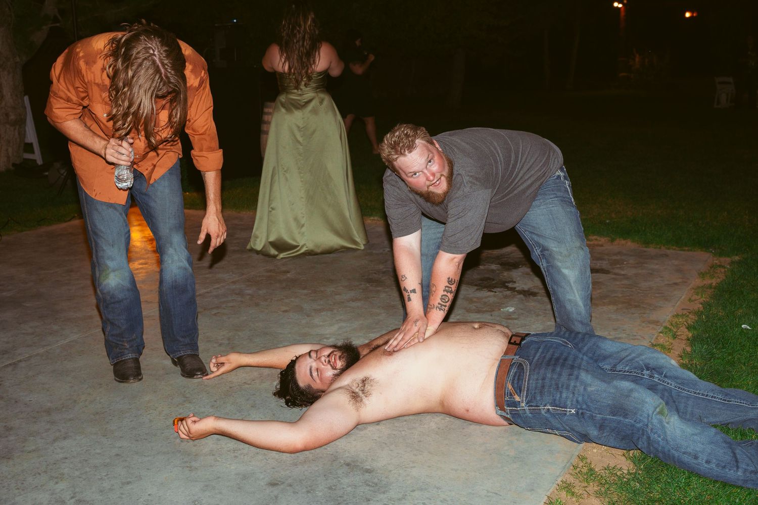 Group of dancers performing dramatic dance moves on a concrete surface at night.