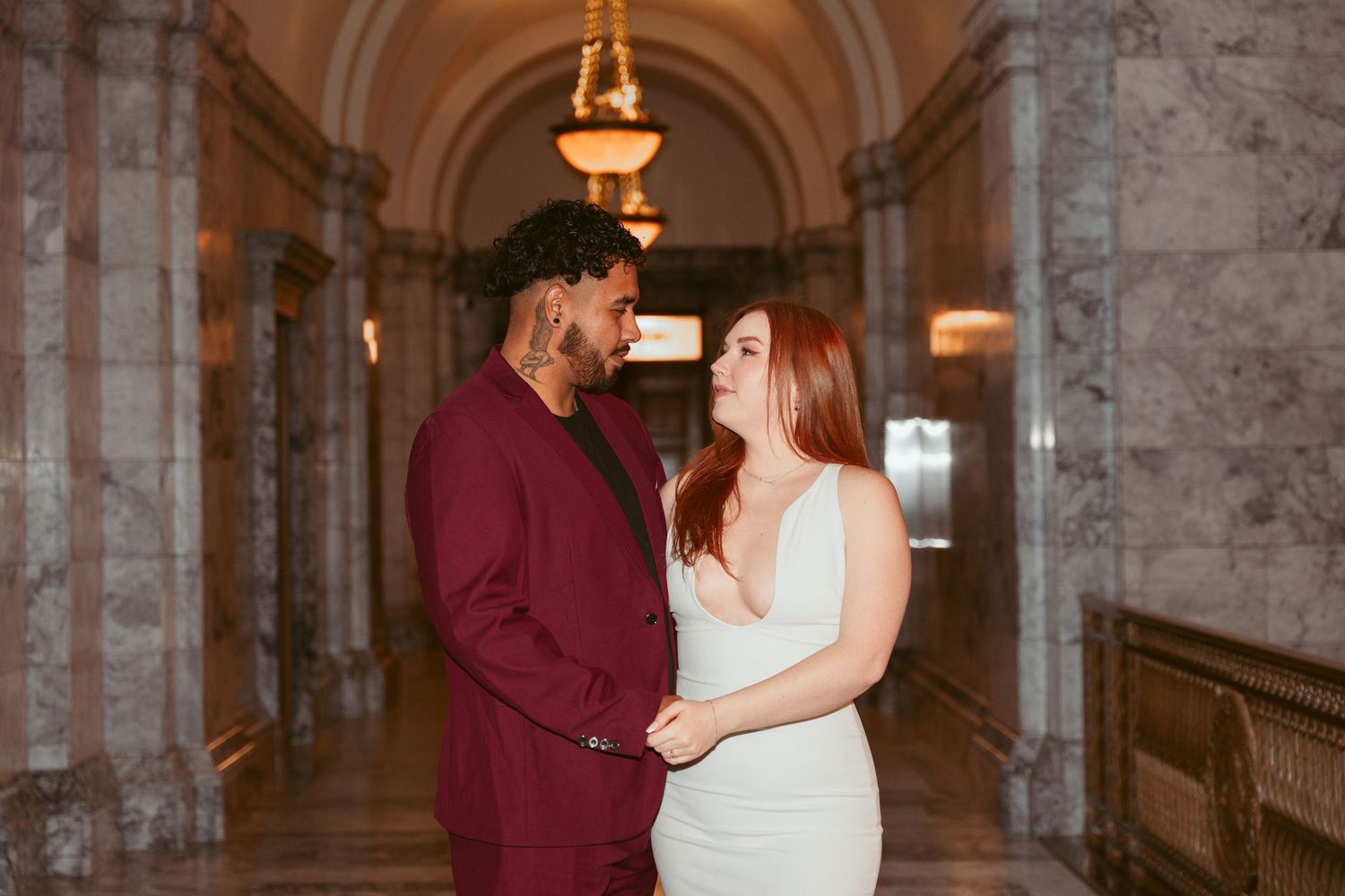 A couple shares tender moments in an elegant marble hallway with arched ceilings.