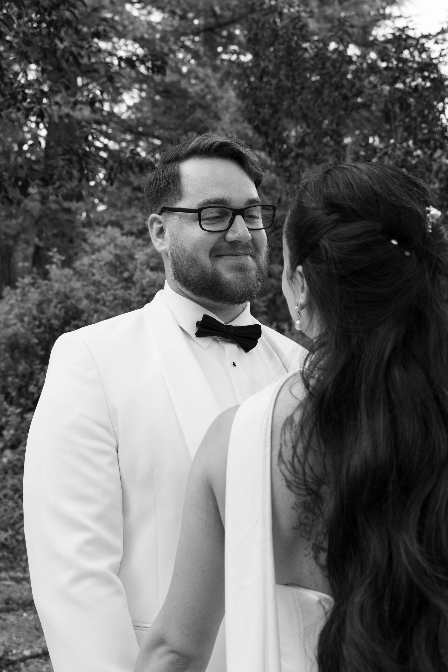 Black and white wedding portraits showing tender moments between newlyweds outdoors.