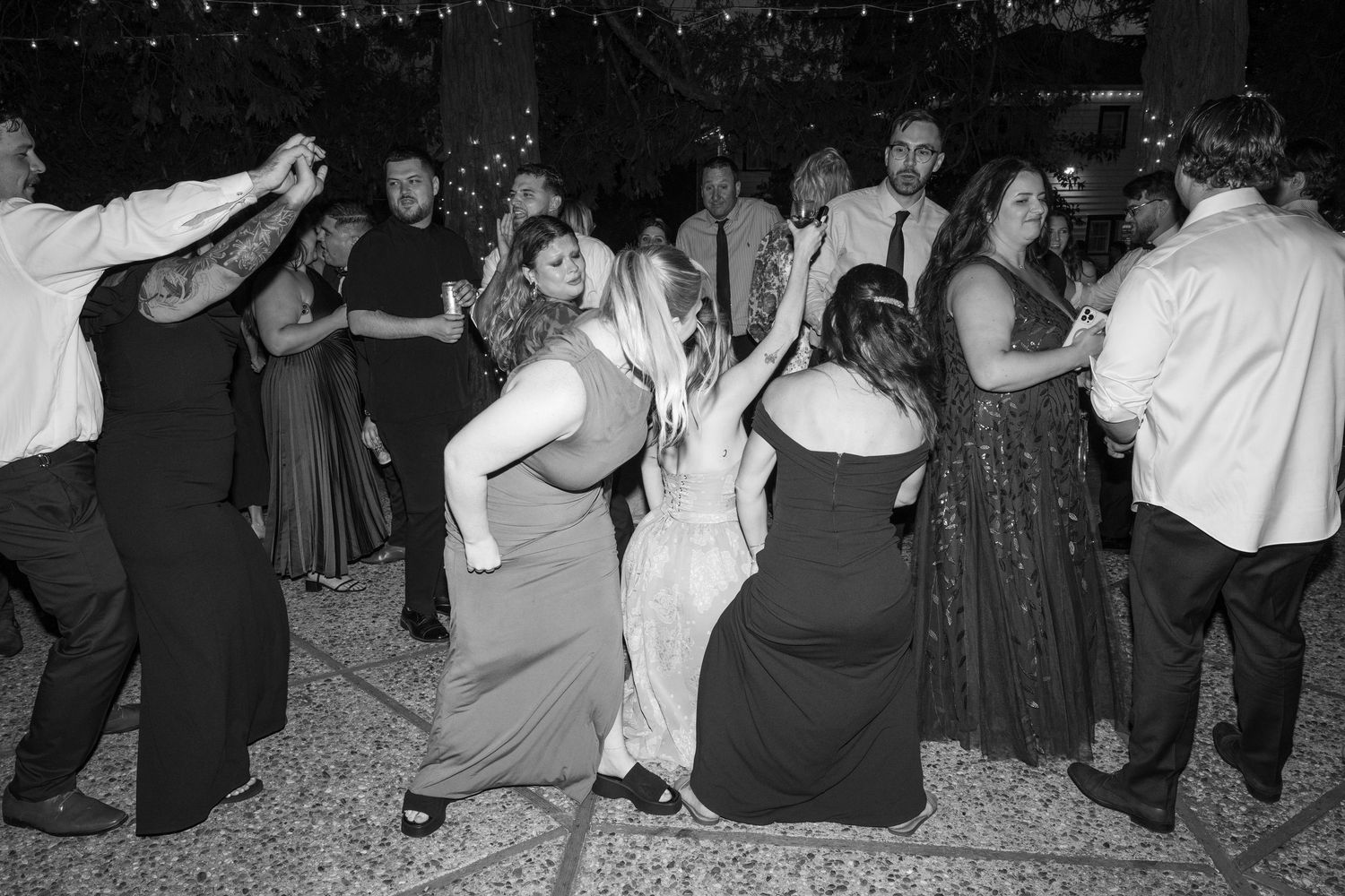 Wedding guests dancing and enjoying themselves at an outdoor evening reception.