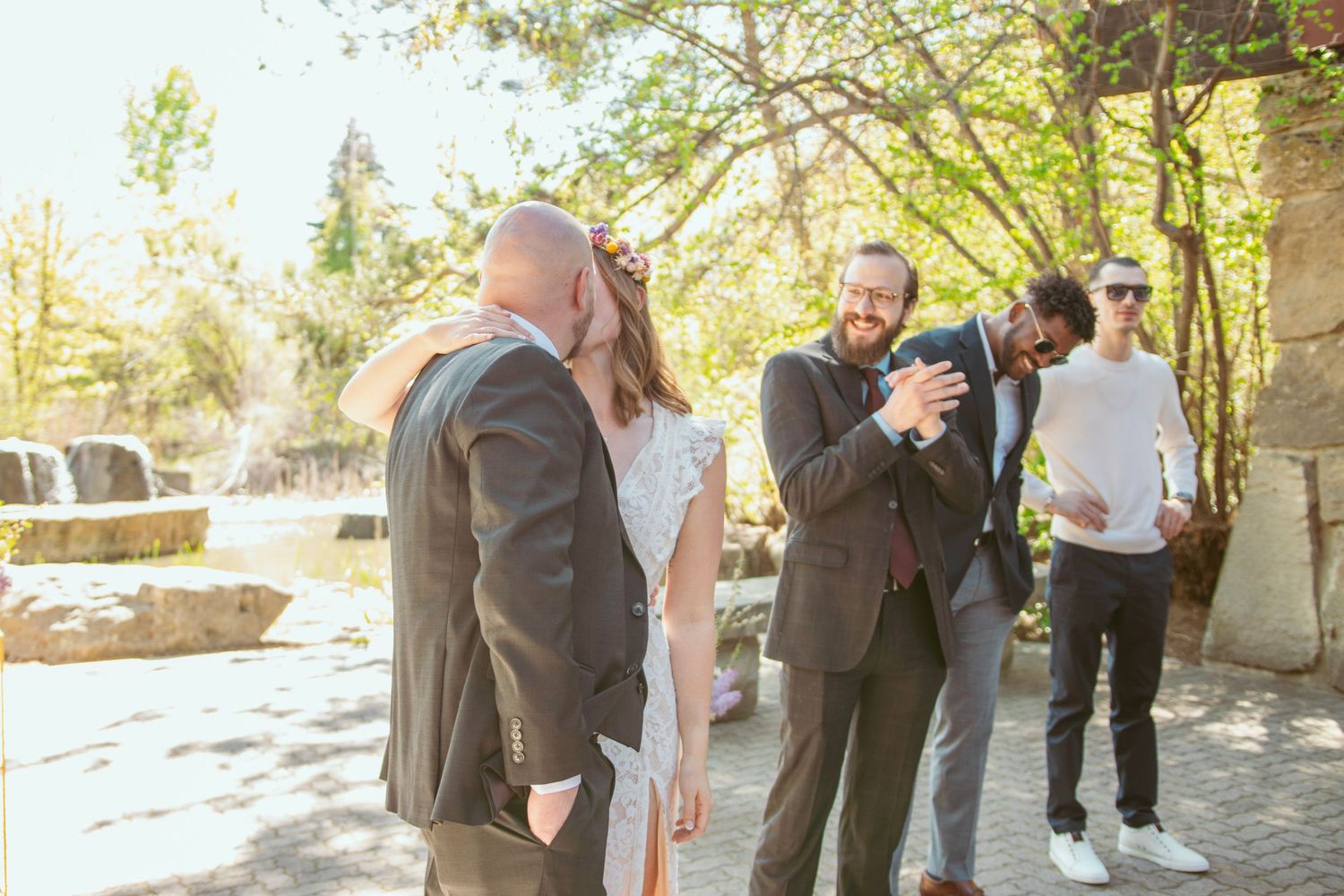 A couple embraces during their outdoor wedding ceremony with guests looking on.