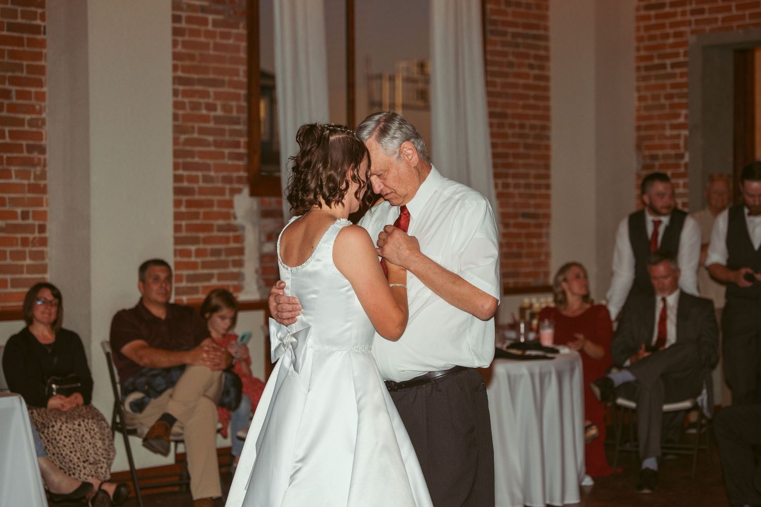 Wedding guests celebrate on the dance floor of a historic brick building venue.