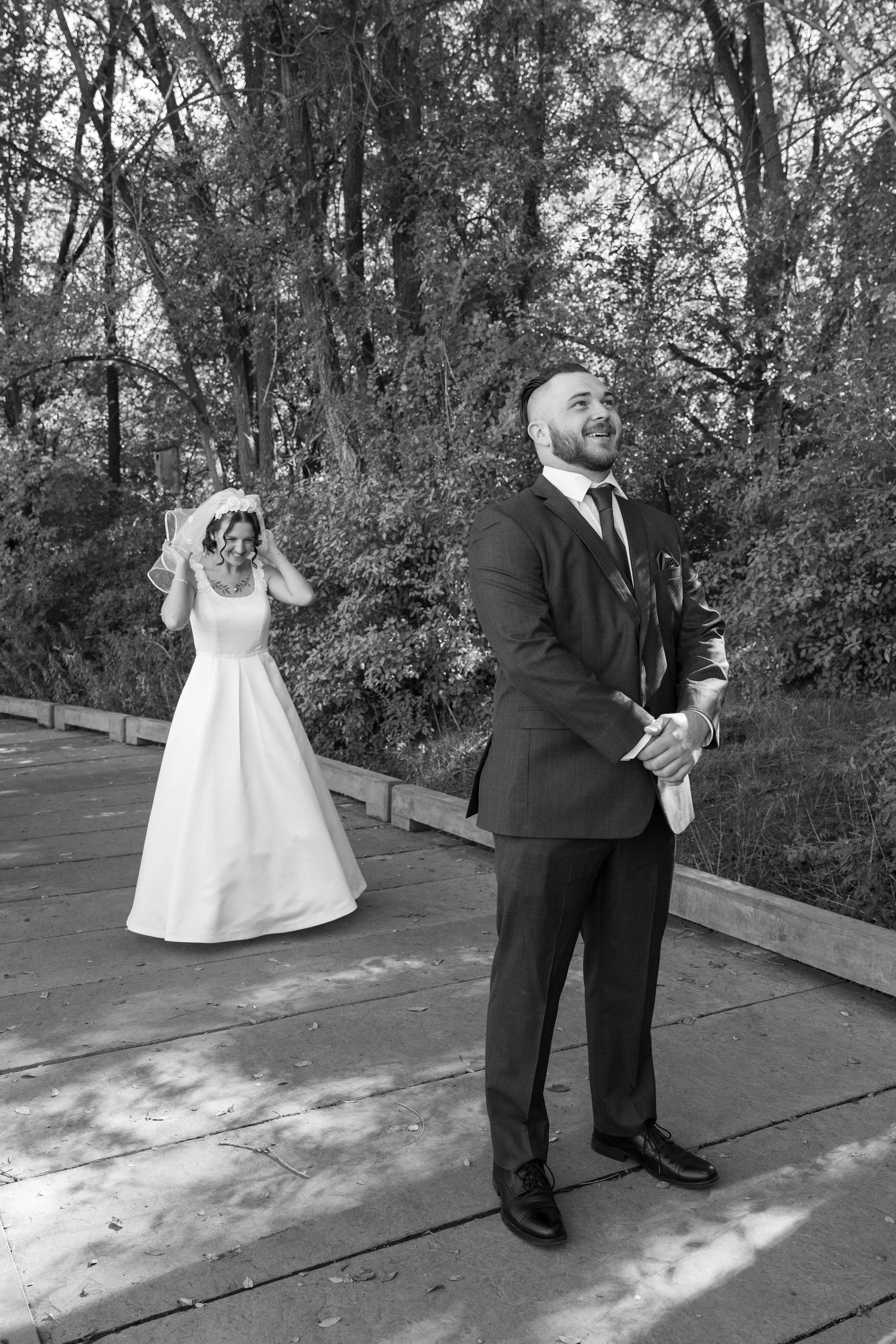 Black and white wedding photo sequence on a wooden deck with natural backdrop.