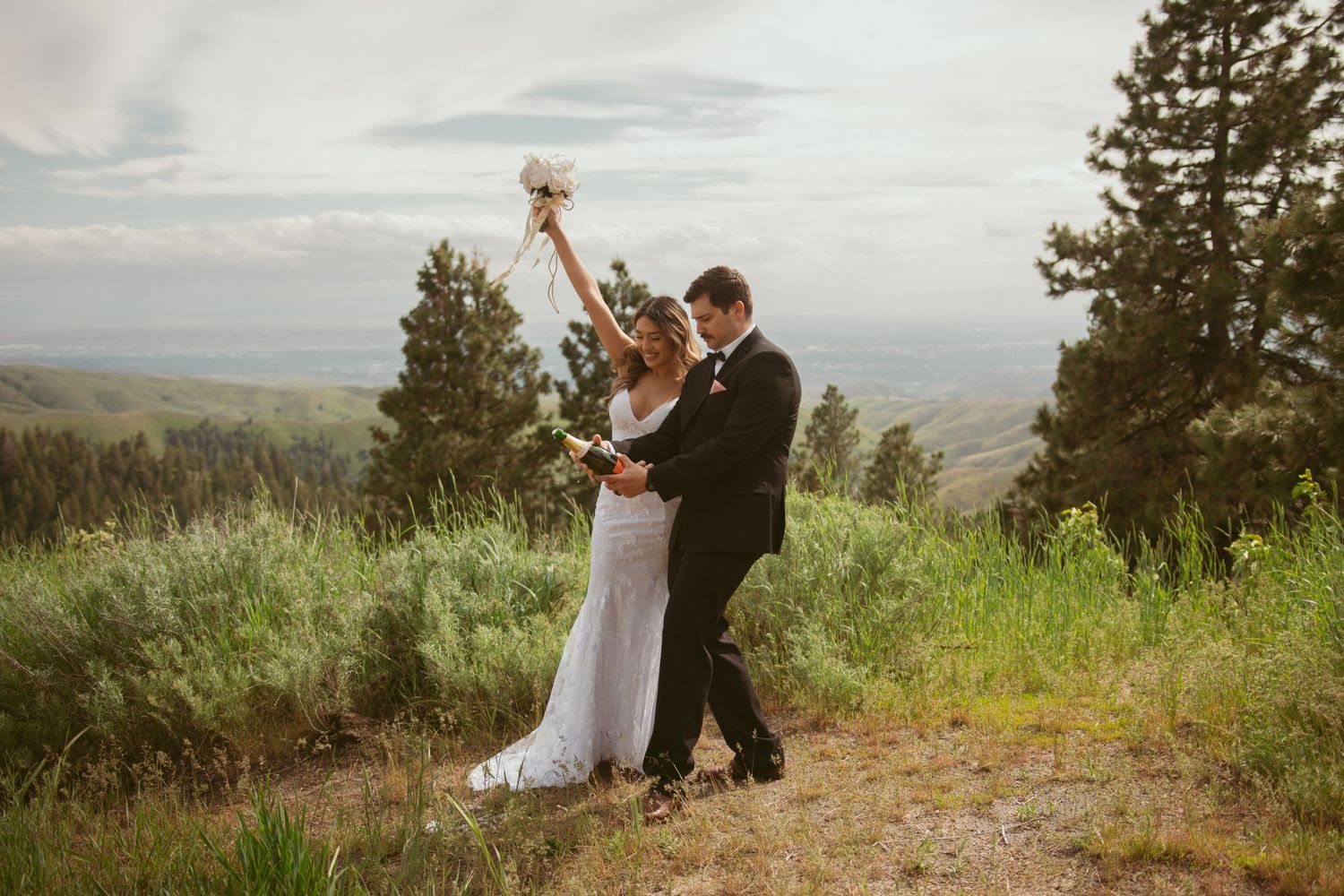 Wedding couple dancing and celebrating against a scenic mountain backdrop.