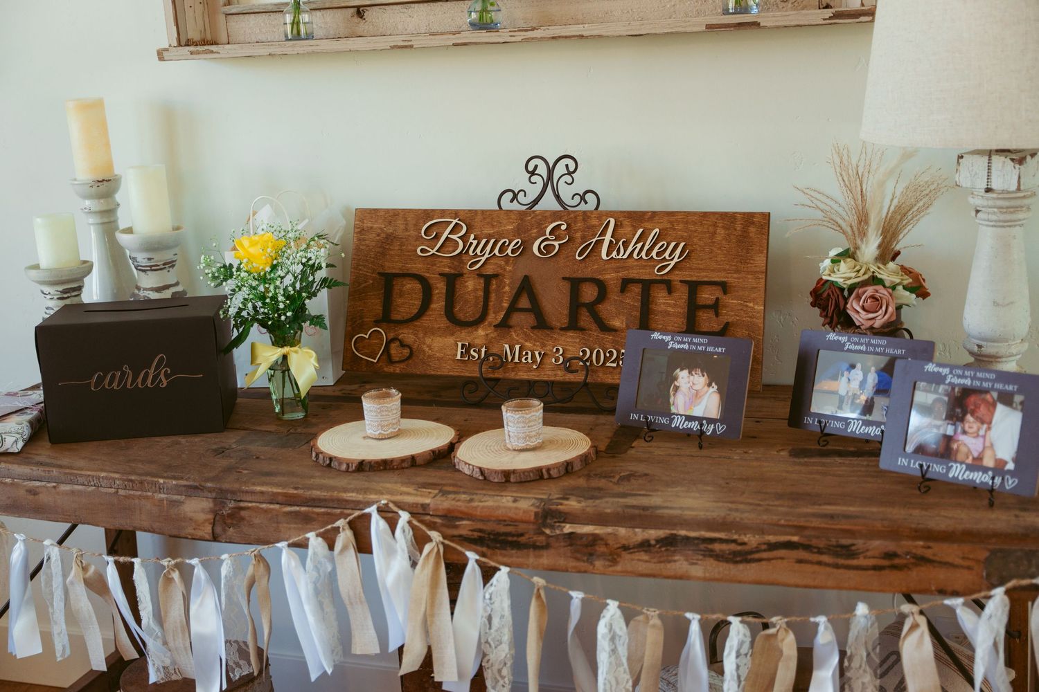 Rustic wedding decor display with wooden sign and fabric garland on live edge table.