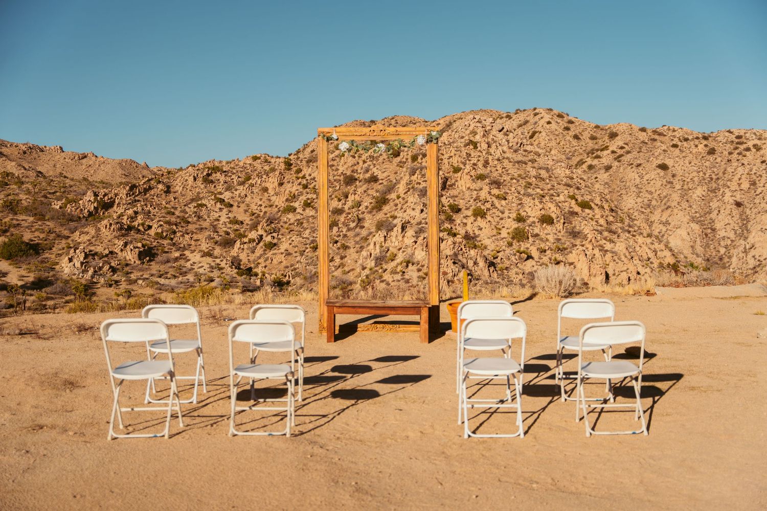 White chairs arranged in rows against a desert landscape with rocky mountains in the background.