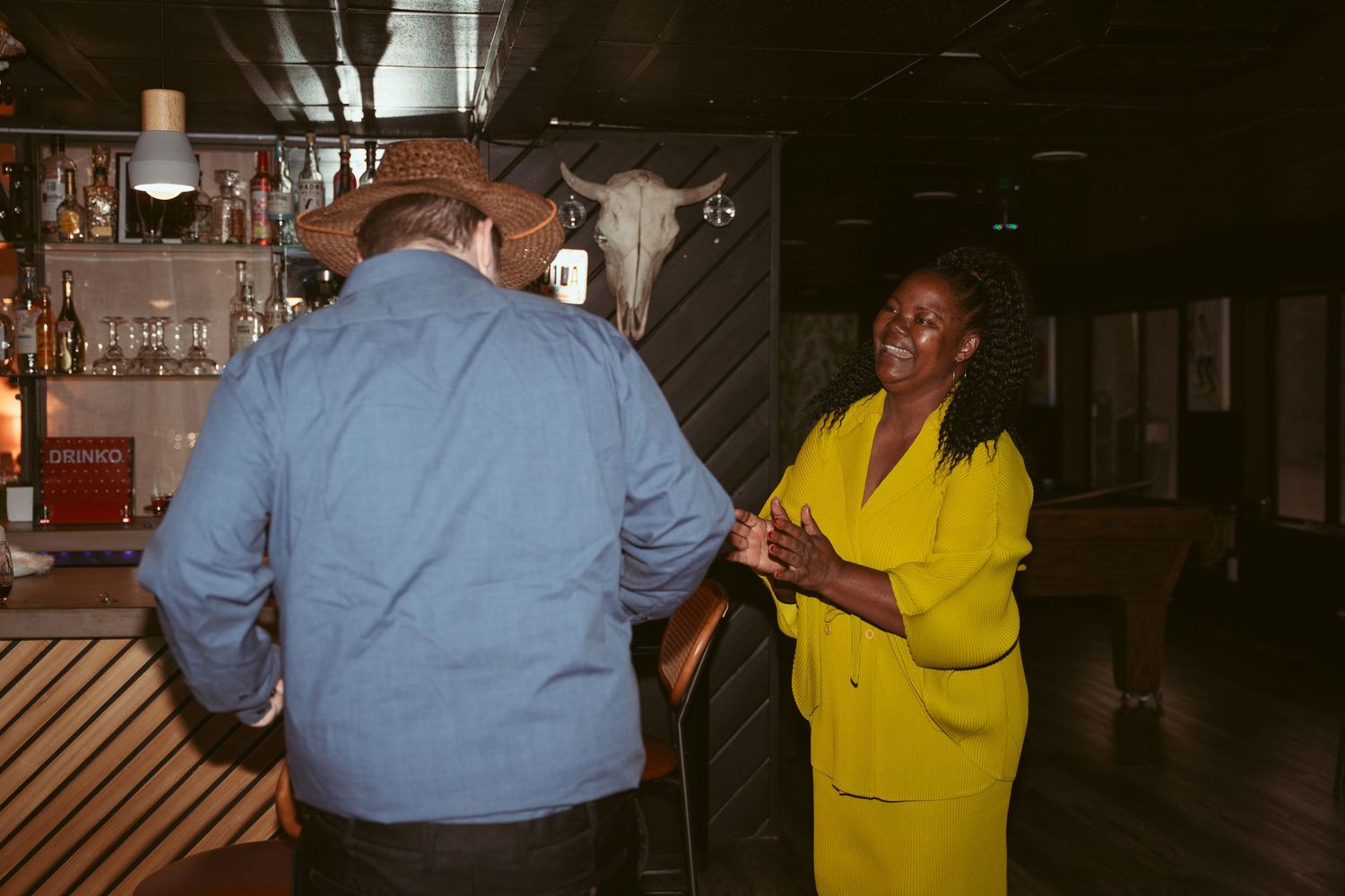 Reception party guests mingling and dancing in a dark venue with mood lighting.