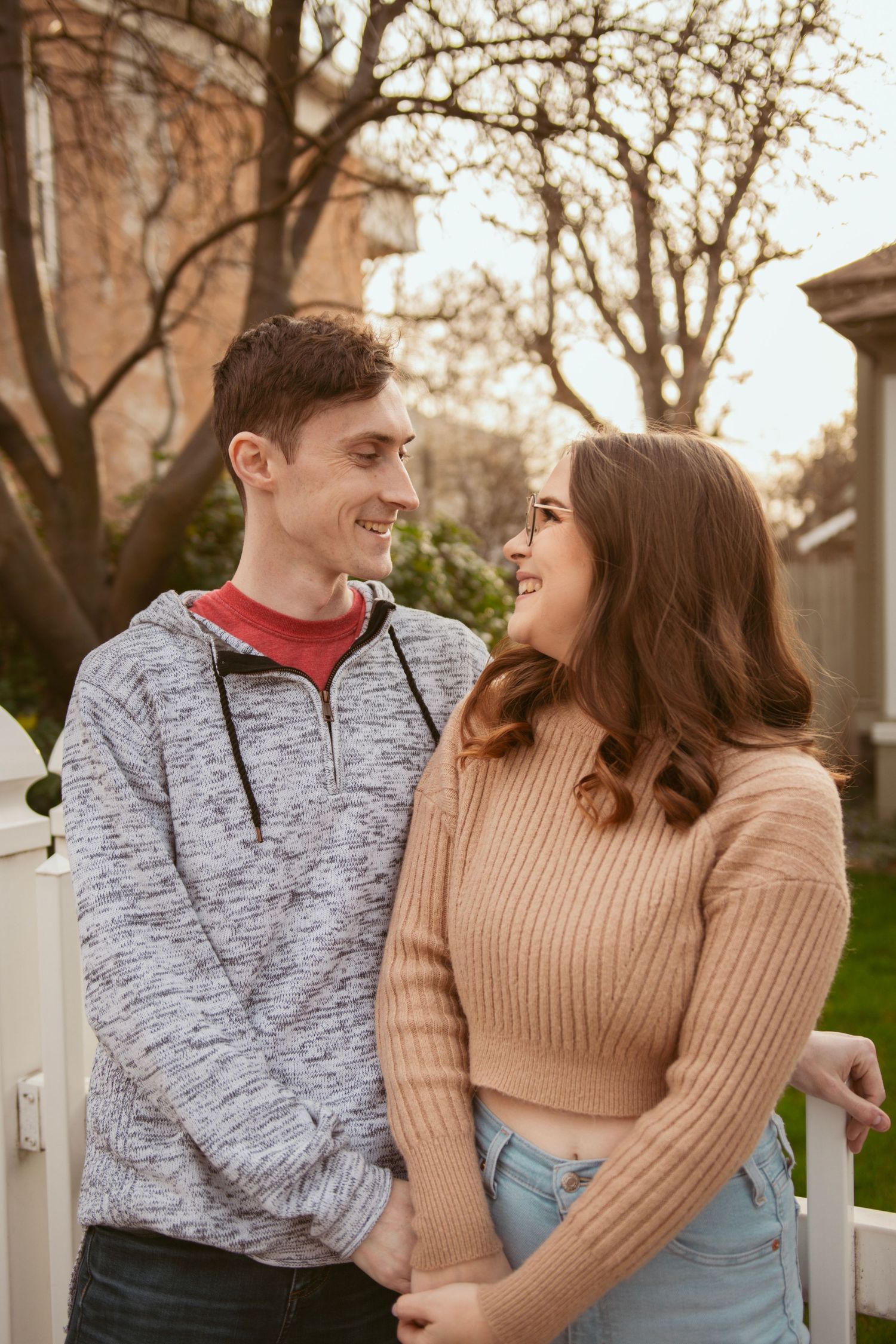 A romantic couple in casual winter wear share a sweet moment together on a porch.