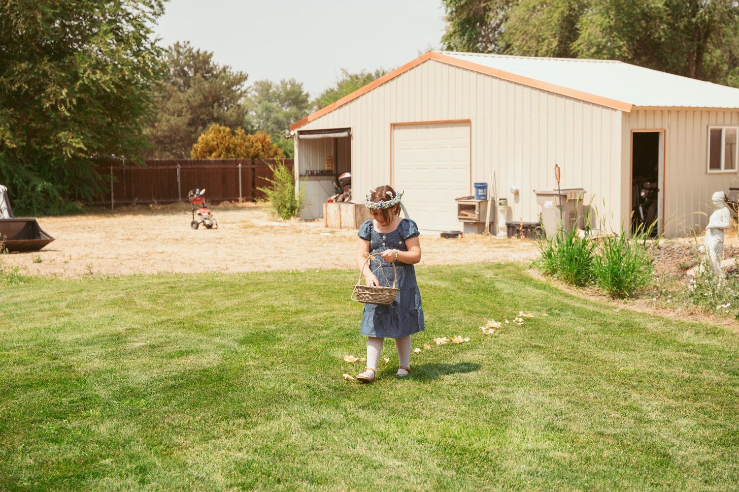 Wide panoramic view of a rustic outdoor wedding venue with green lawn and buildings.