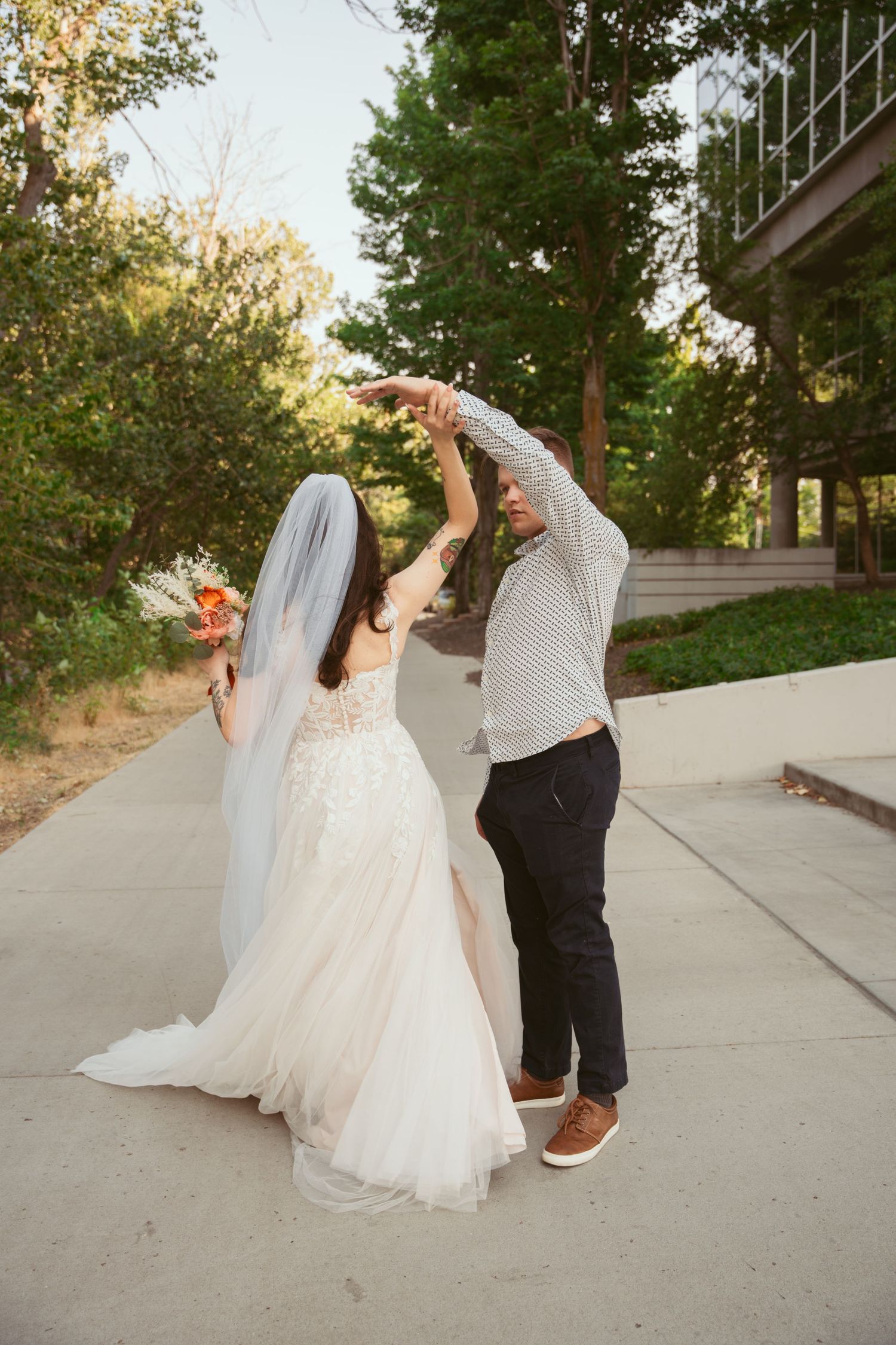 Newlyweds taking shots together on outdoor path at sunset.