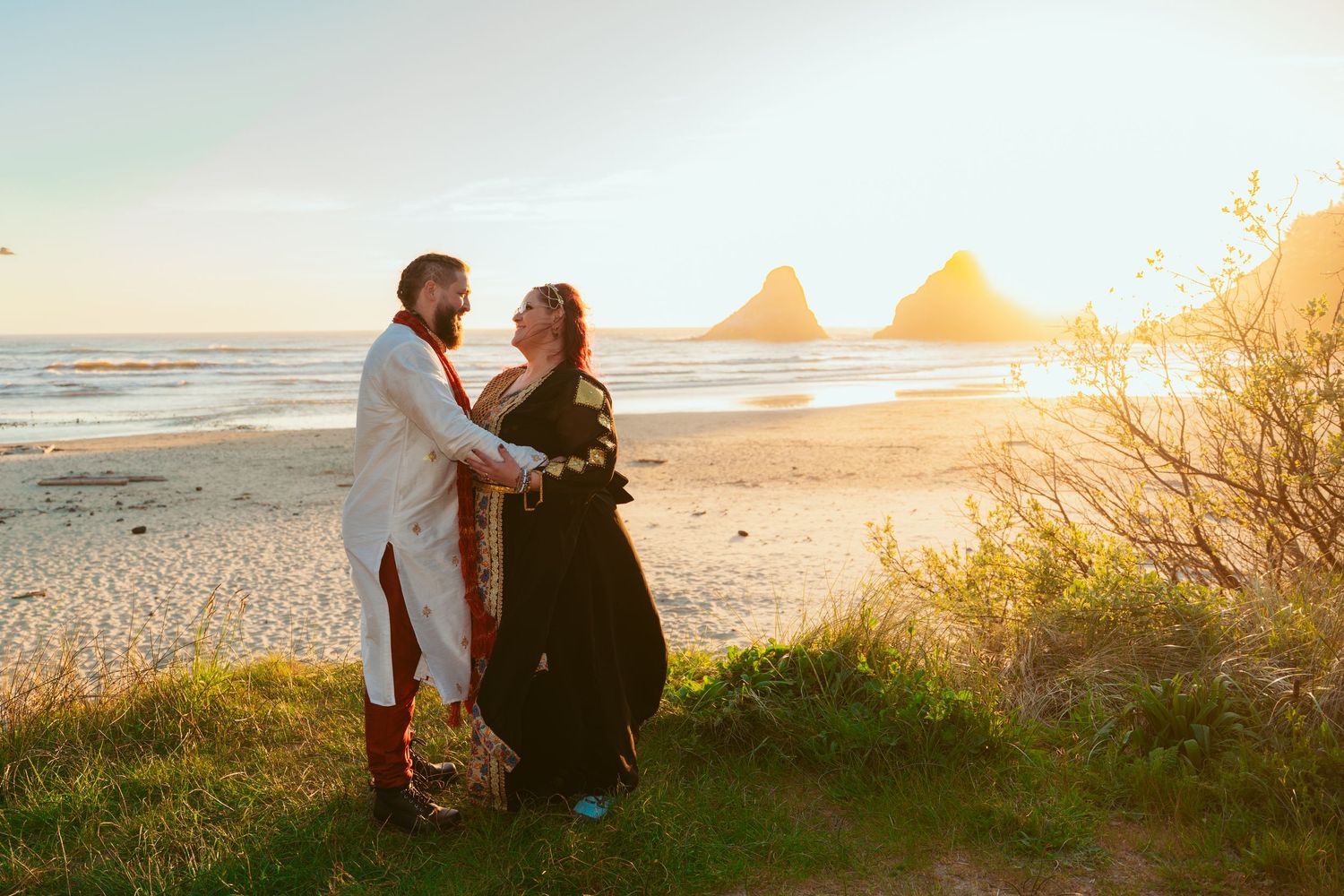 A romantic sunset beach proposal scene with ocean waves and rock formations in the background.