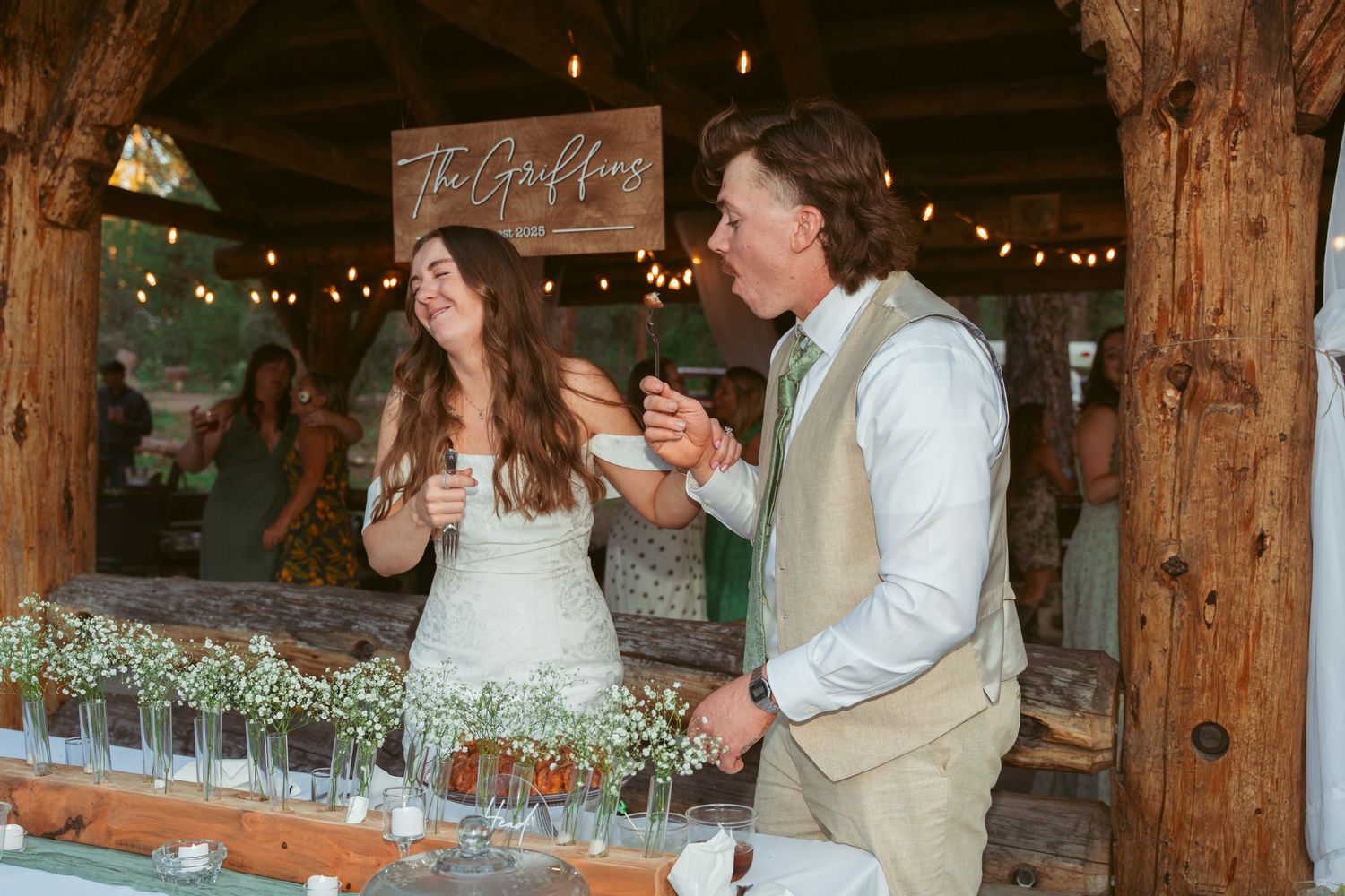 Couple shares a romantic dance moment at a rustic barn wedding reception with string lights and wooden beams.