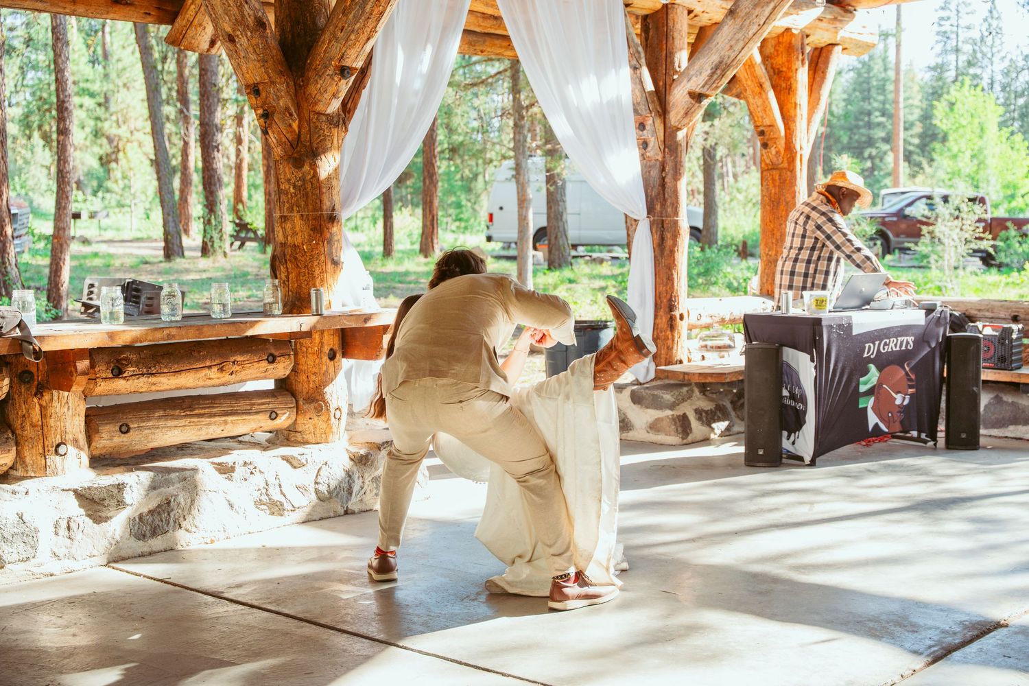 Outdoor wedding venue with wooden beams and white curtains framing a special dance.